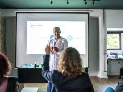 Teacher doing a presentation and student raising hand during chemistry class